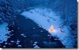 Illuminated Christmas tree beside a creek in a snow covered forest at dusk, Cascade Mountains, Washington, USA