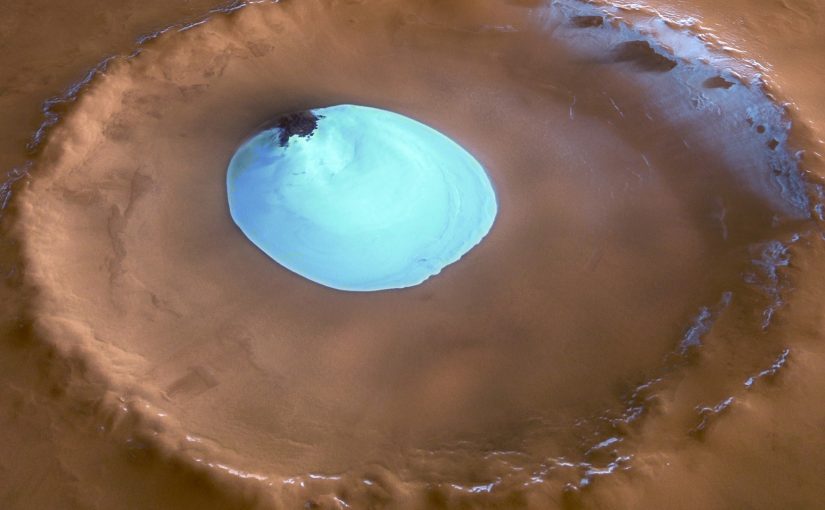 Vista de un cráter sin nombre en las latitudes septentrionales de Marte. El cráter tiene 35 km de ancho y una profundidad máxima de aproximadamente 2 km por debajo del borde del cráter. El parche circular de material brillante ubicado en el centro del cráter es hielo de agua residual.